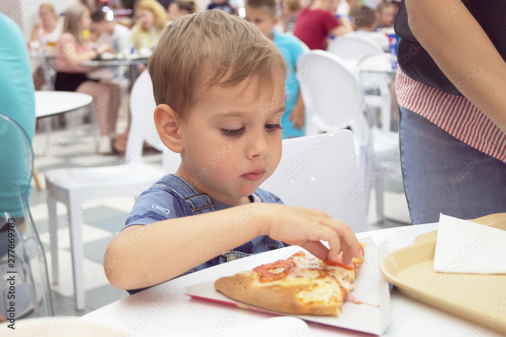 children teens eat pizza in a cafe where a lot of people children teens eat pizza in a cafe where a lot of people