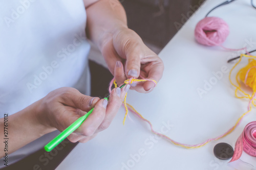 girl knits yarn with knitting needles and crochet at home. in a white t-shirt. hand knits