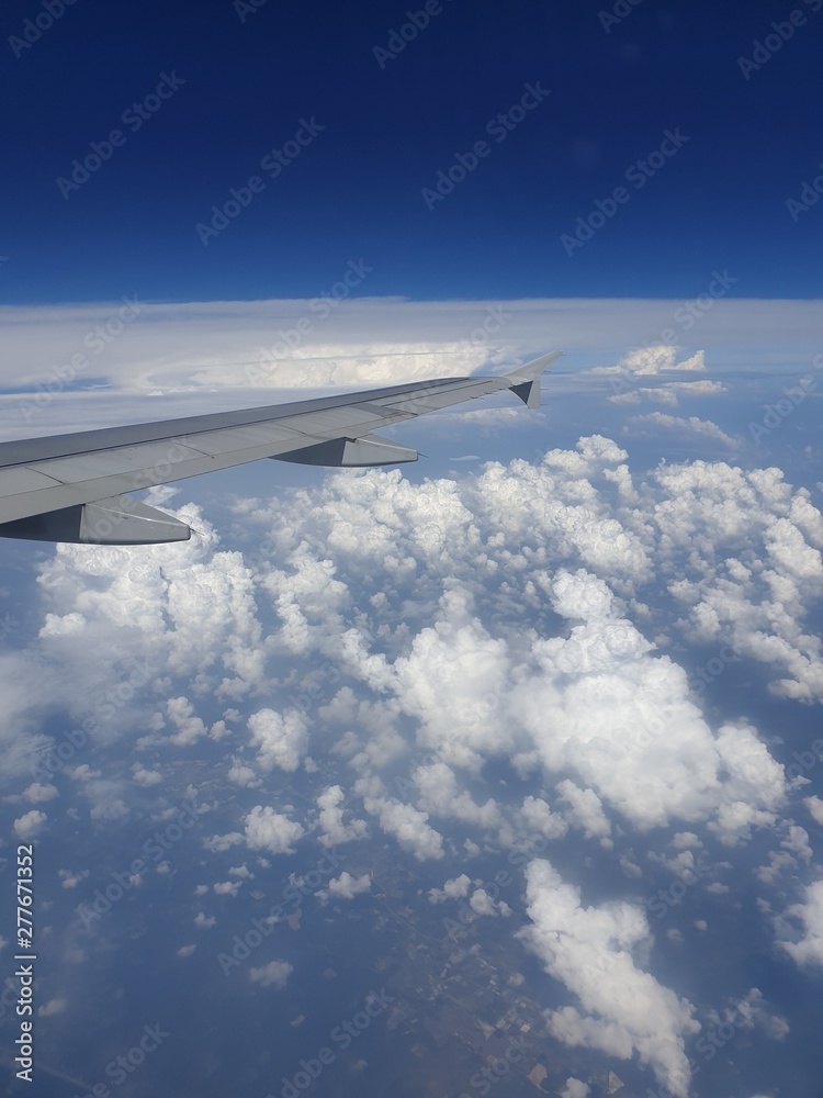 Obraz premium wing of an airplane flying above the clouds