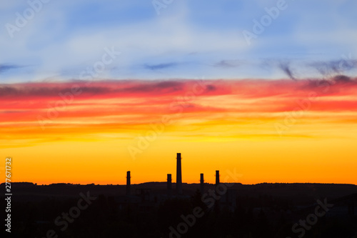 Industrial panorama on the background of a colorful dramatic sky with clouds at sunset.
