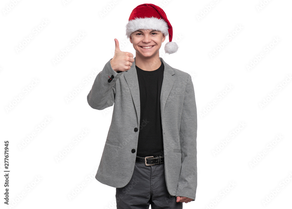 Portrait of teen boy with Christmas hat. Teenager wearing grey suit, smiling and looking at camera. Holiday concept - happy cute child isolated on white background. Portrait of teen boy with Christmas hat. Teenager wearing grey suit, smiling and looking at camera. Holiday concept - happy cute child isolated on white background.