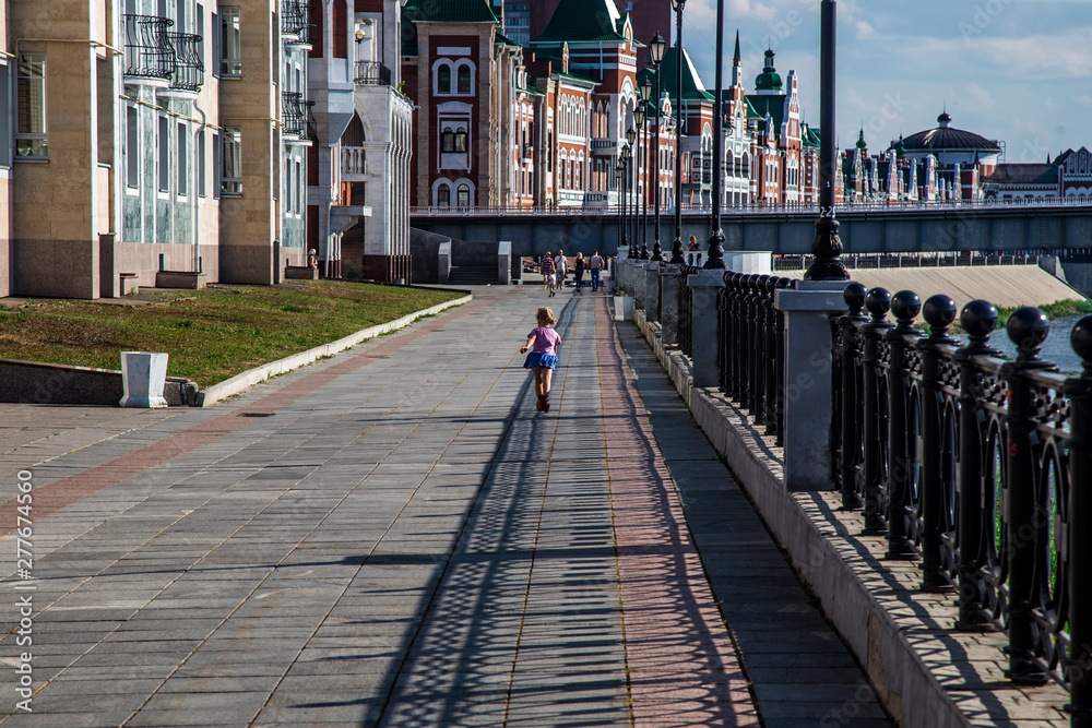 little girl running along the promenade on a hot summer day