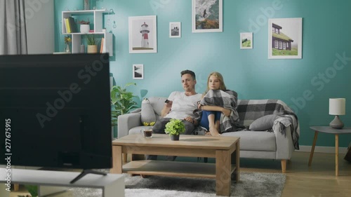 Bored young couple watching tv on the couch
