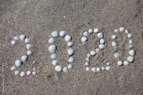 The figure "2020" is laid out on sand with shells. There is free space, space for text.