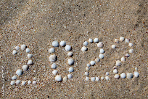 The figure "2022" is laid out on sand with shells. There is free space, space for text.