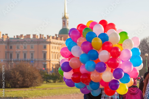 Many colorful balloons are a symbol of celebration, party - group of children in city center are sightseeing