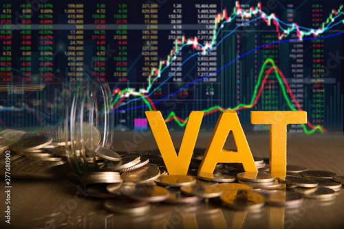 Vat Concept.Word vat put on coins and glass bottles with coins inside on black background.Stock market or forex trading graph and candlestick chart photo