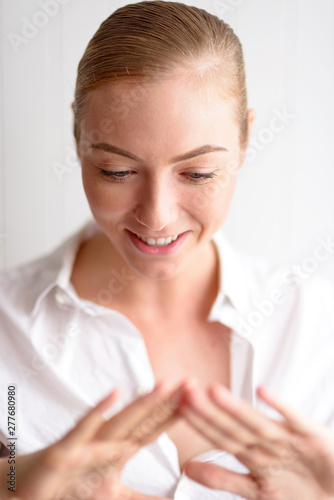 Emotion Concept. Woman standing isolated on white looking down at hands fascinated close-up