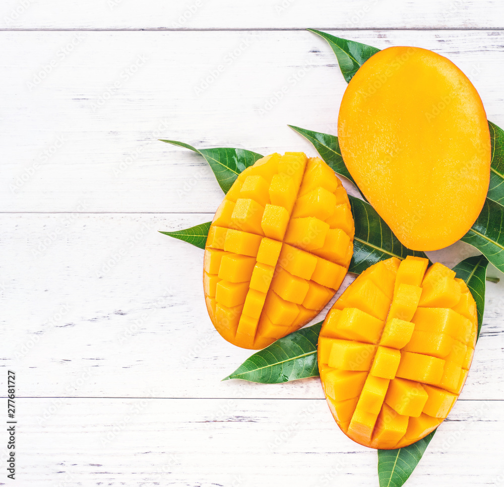 Beautiful chopped mango with green leaves on bright white color timber background. Above Top view, flat lay, copy space, close up. Tropical fruit concept. Beautiful chopped mango with green leaves on bright white color timber background. Above Top view, flat lay, copy space, close up. Tropical fruit concept.