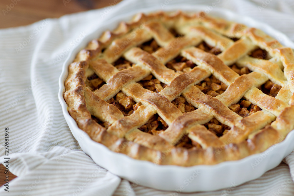 food, culinary and baking concept - close up of apple pie in mold on kitchen towel food, culinary and baking concept - close up of apple pie in mold on kitchen towel