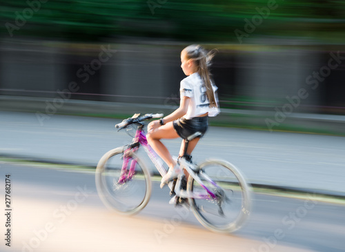 Girl cyclist in motion going down the street
