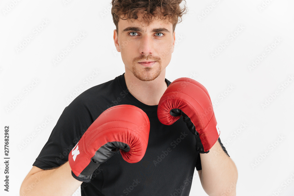 Photo closeup of focused man in t-shirt looking at camera while boxing in gloves