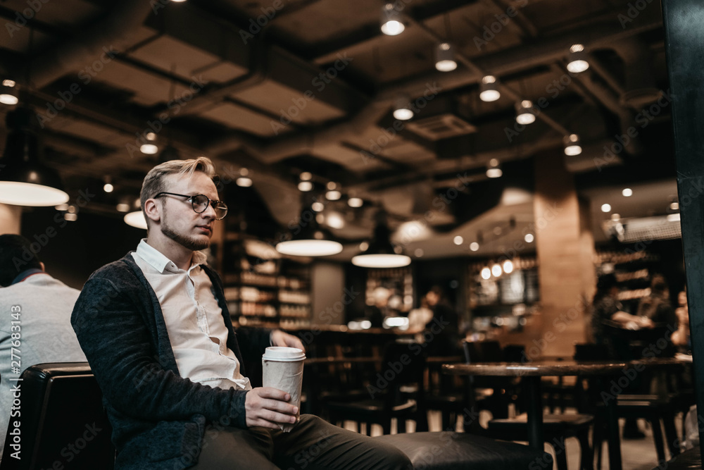 European man blond in a cafe with a glass of coffee enjoys the day. European man blond in a cafe with a glass of coffee enjoys the day.