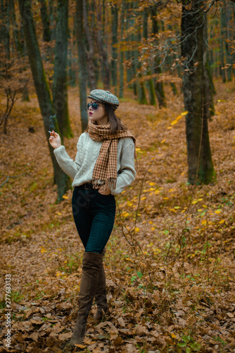 Autumnal melancholy. Autumn is here. Pretty woman in hat and sunglasses smoking cigarette forest background. Fall fashion accessory. Enjoy fall season. Relaxing smoking. Woman enjoy smoking alone