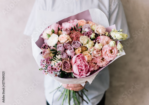 Wallpaper Mural very nice young man holding a beautiful blossoming flower bouquet of fresh peony, roses, eustoma,carnations, in tender pink colors on the grey wall background Torontodigital.ca