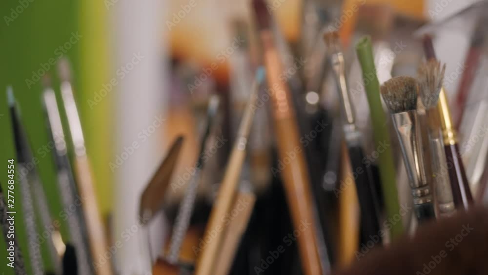 Close up slide over many paint brushes in jars and pots. Close up slide over many paint brushes in jars and pots.