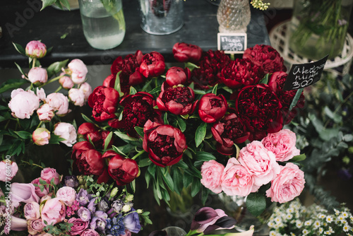 Beautiful flowers at the florist shop: fresh crimson peonies in a vase surrounded by other flowers