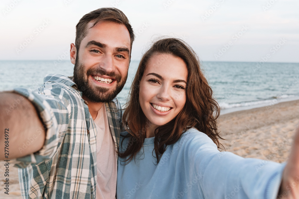 Obraz premium Beautiful young smiling couple spending time at the beach