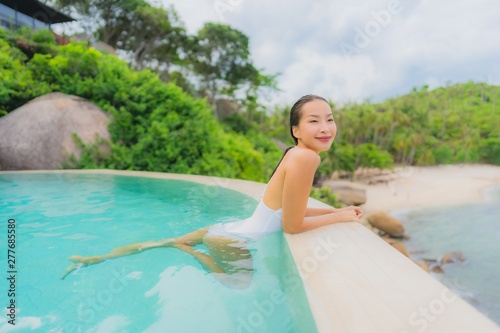 Portrait young asian woman relax smile happy around outdoor swimming pool in hotel resort with sea ocean view © siraphol