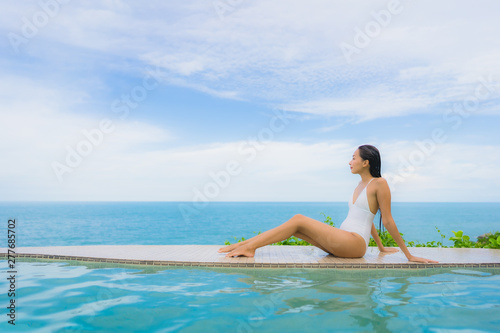 Portrait young asian woman relax smile happy around outdoor swimming pool in hotel resort with sea ocean view