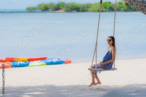 Portrait young asian woman sitting on swing rope and sea around beach sea ocean coconut palm tree for travel in holiday © siraphol