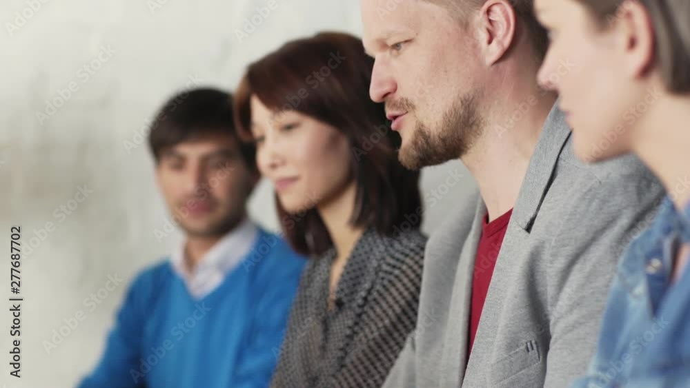 Group of four diverse business people watching and discussing presentation. Focus on middle aged man sharing his opinion with colleagues Group of four diverse business people watching and discussing presentation. Focus on middle aged man sharing his opinion with colleagues