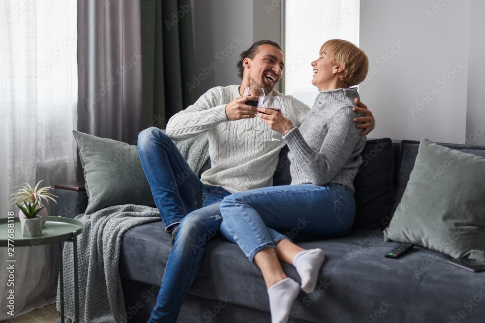 Couple laughing and drinking wine at home