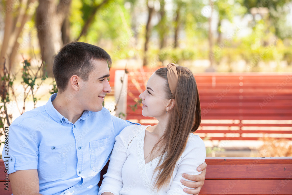 Young couple sitting on bench in park.