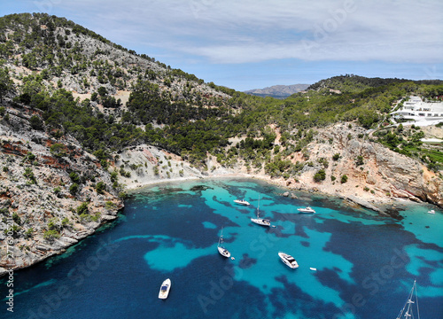 Drone point of view aerial photo moored yachts on the bright blue bay on the Cala Blanca Andratx in the Palma de Mallorca, rocky coast breathtaking view, Balearic Islands Spain.
