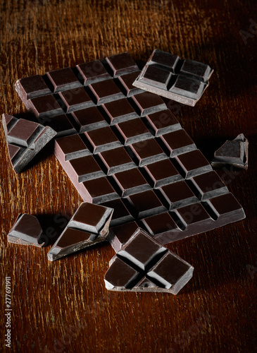 Chocolate bar and chunks on vintage wooden background. Sweet food photo concept photo