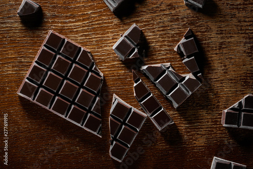 Chocolate bar and chunks on vintage wooden background. Sweet food photo concept. Top view photo