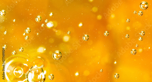 Bubbles of air on the smooth surface of golden water as an abstract background