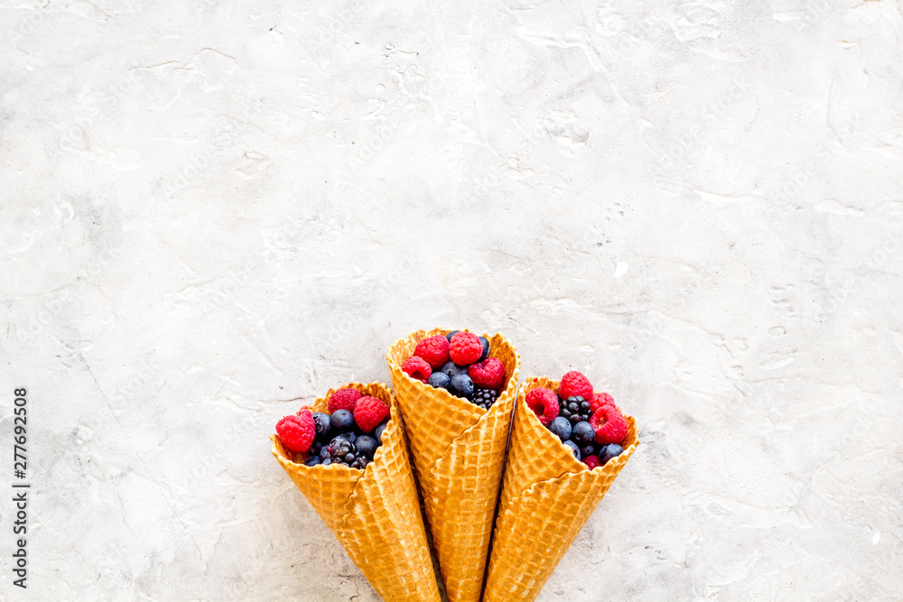 Fresh berries in waffle cones on light stone background top view mock up