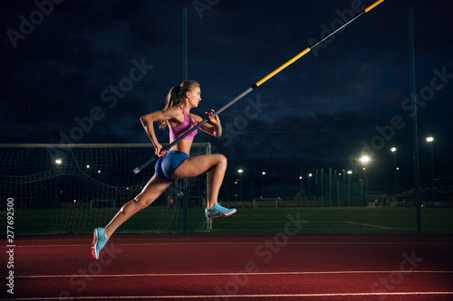Ready to overcome difficulties. Professional female pole vaulter training at the stadium in the evening. Practicing outdoors. Concept of sport, activity, healthy lifestyle, action, movement, motion.