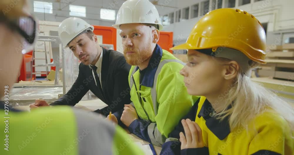 Close up of group of engineers discussing a production plan in a factory. Close up of group of engineers discussing a production plan in a factory.