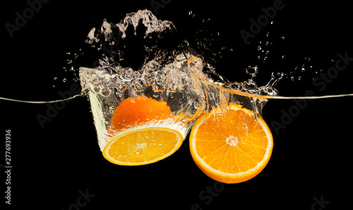 Fototapeta Naklejka Na Ścianę i Meble -  Fresh ripe oranges splashing into water with splash