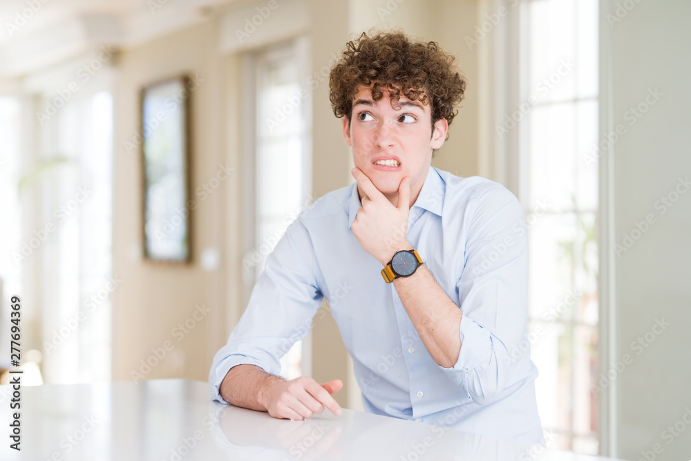 Young business man with curly read head Thinking worried about a question, concerned and nervous with hand on chin