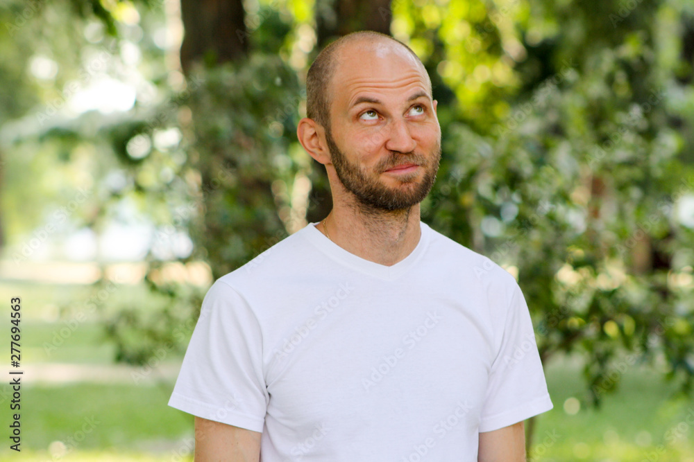 Close portrait of happy man in white T-Shirt creating an interesting idea and wrinkling his forehead Close portrait of happy man in white T-Shirt creating an interesting idea and wrinkling his forehead