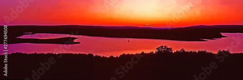An impressive sunset over Kielder Water Northumberland with single yacht sailing away from the Marina