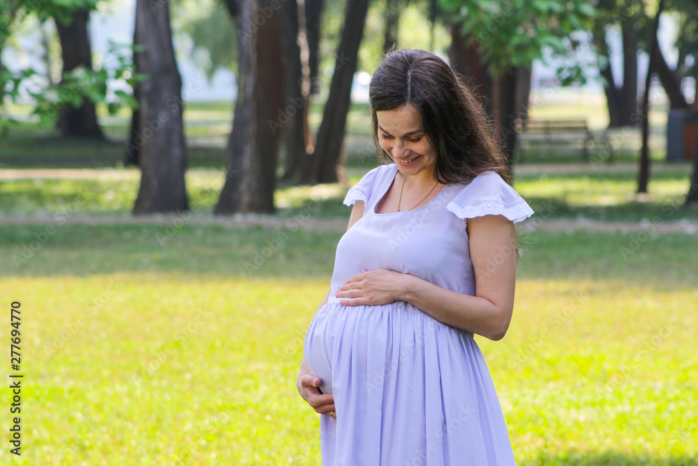 Portrait of beautiful young woman supporting her big pregnant belly with both hands. Portrait of beautiful young woman supporting her big pregnant belly with both hands.