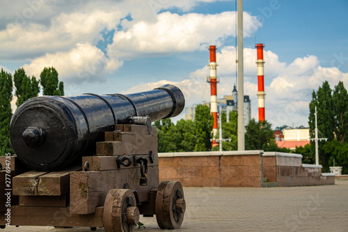 Replica of cannon on  Admiralty Square on clear sunny day. Close-up. In background are two pipes of heat and power plant. Voronezh, Russia, June, 2019. 