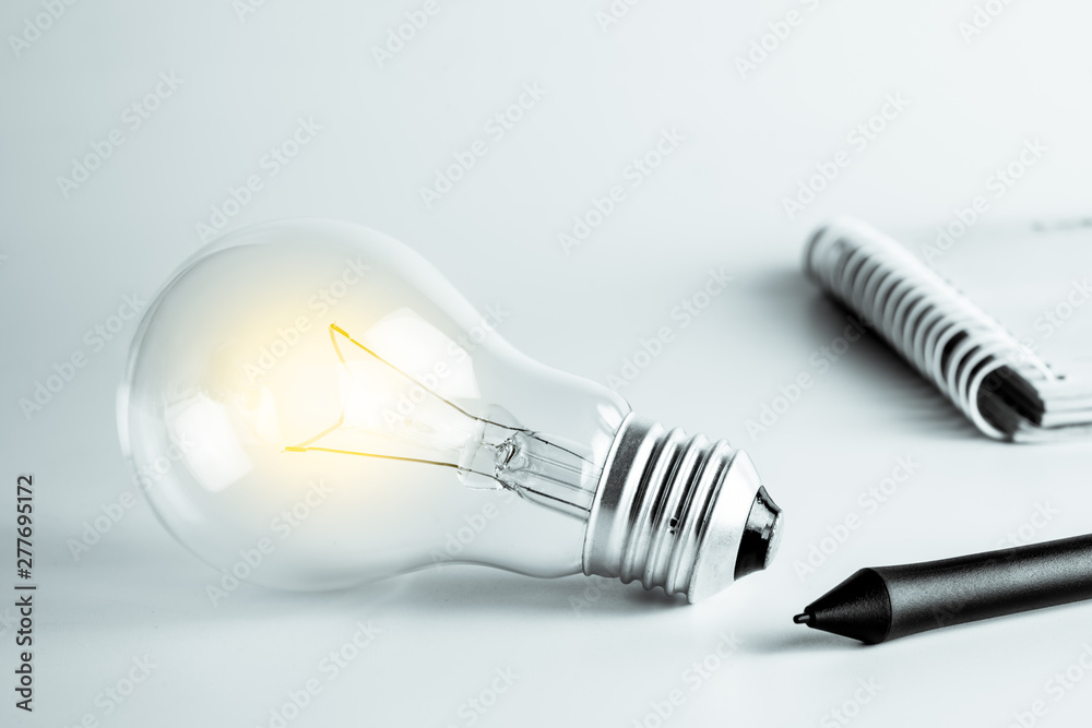 New idea, innovation and solution concept with Light bulbs, pen and open spiral notebook New idea, innovation and solution concept with Light bulbs, pen and open spiral notebook