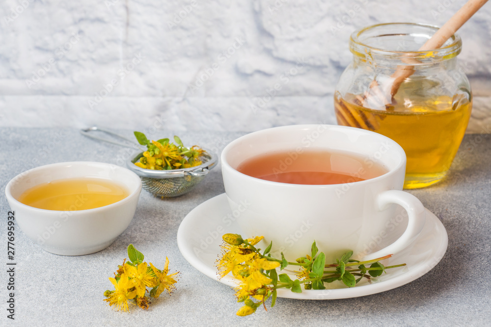 Cup with herbal tea from petals flowers Hypericum on grey background. Copy space.