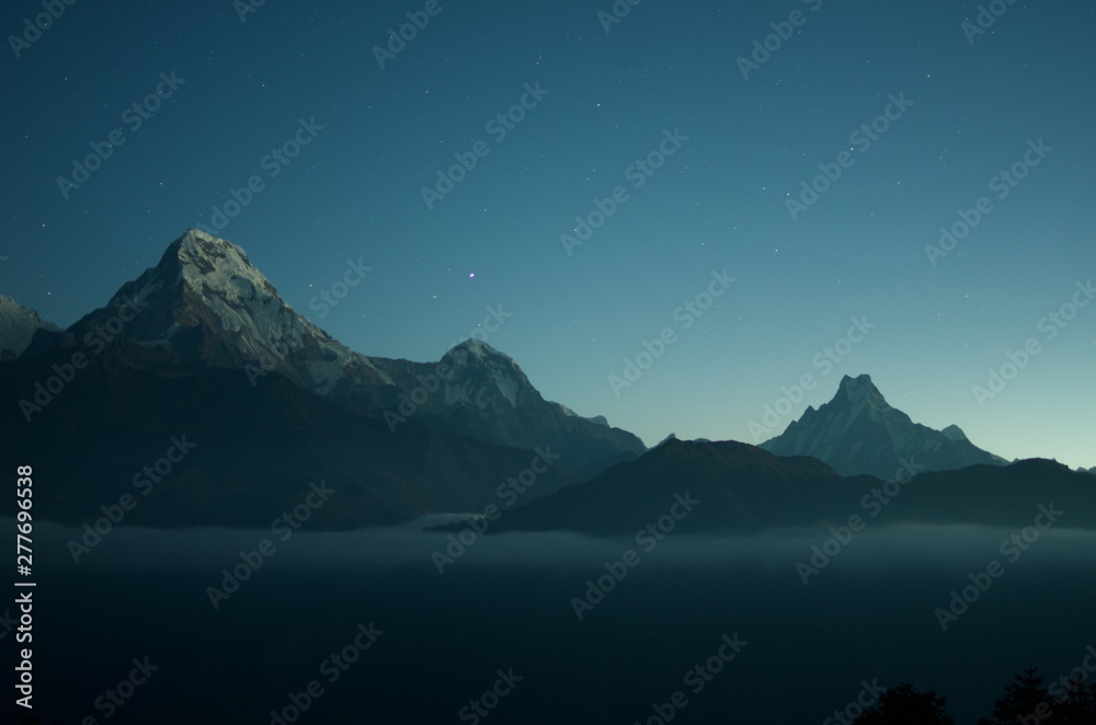 Wide shot of beautiful rocky mountains with amazing clear blue sky with stars in the background - obrazy, fototapety, plakaty 