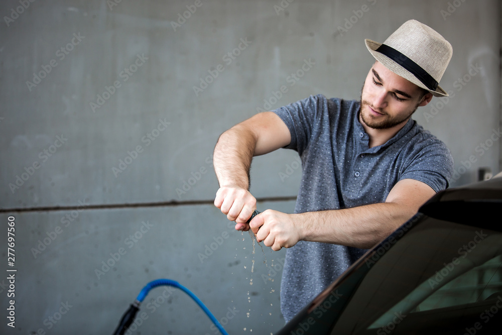 Young man washing his car in car wash