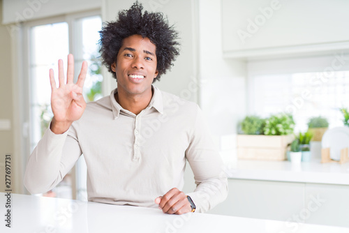 African American man at home showing and pointing up with fingers number four while smiling confident and happy.