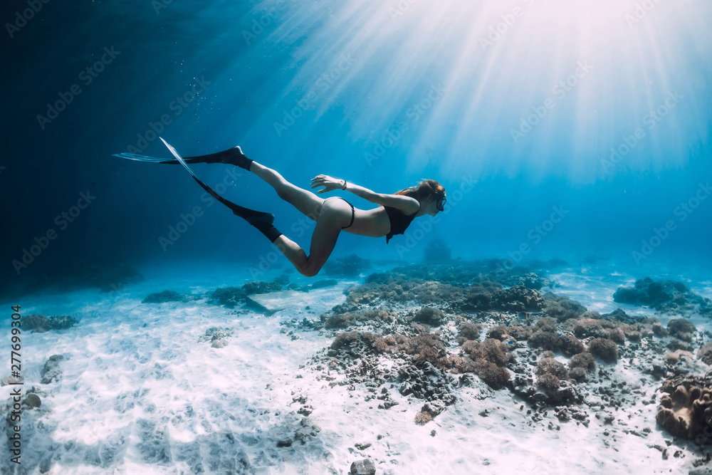 Free diver glides over sandy sea with fins. Freediving in blue sea