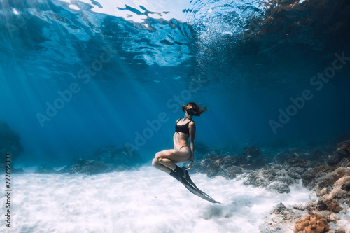 Woman freediver posing over sandy sea with fins. Freediving in Hawaii