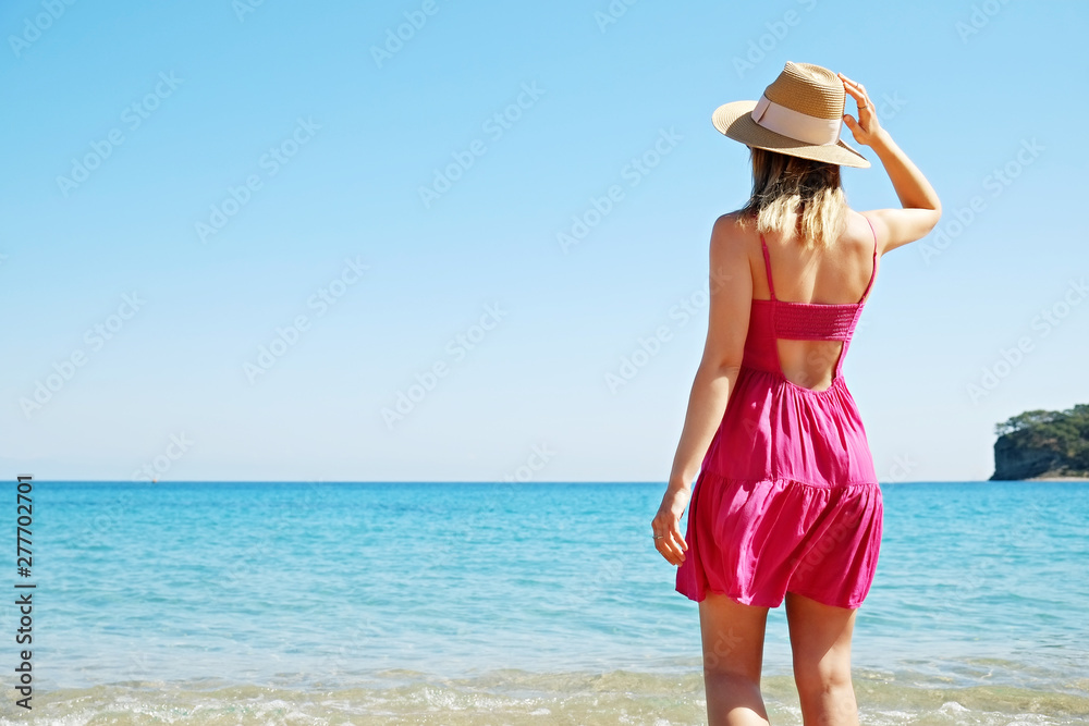 Attractive fit young woman in pink dress at sandy beach watching sea horizon. Attractive fit young woman in pink dress at sandy beach watching sea horizon.
