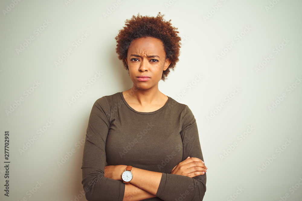Young beautiful african american woman with afro hair over isolated background skeptic and nervous, disapproving expression on face with crossed arms. Negative person. Young beautiful african american woman with afro hair over isolated background skeptic and nervous, disapproving expression on face with crossed arms. Negative person.